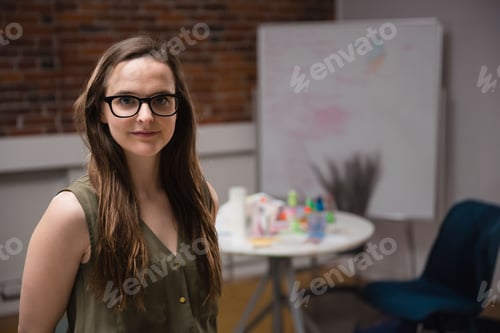 Preview: Woman olive-green top standing left of meeting room table with markers notes whiteboard copy space