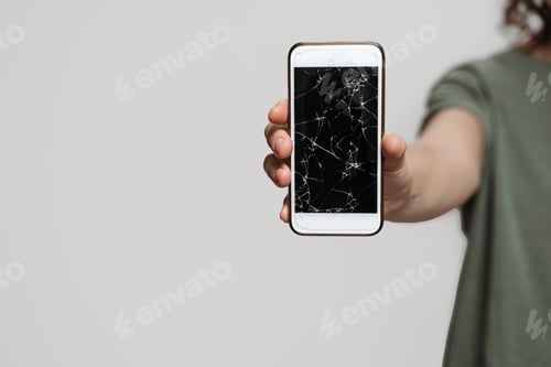 Preview: Close up, hand holding broken smartphone with damaged screen protection