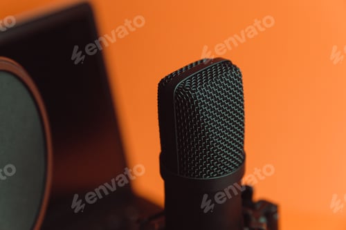 Preview: Close up mock up of a streaming microphone with a laptop over an orange background