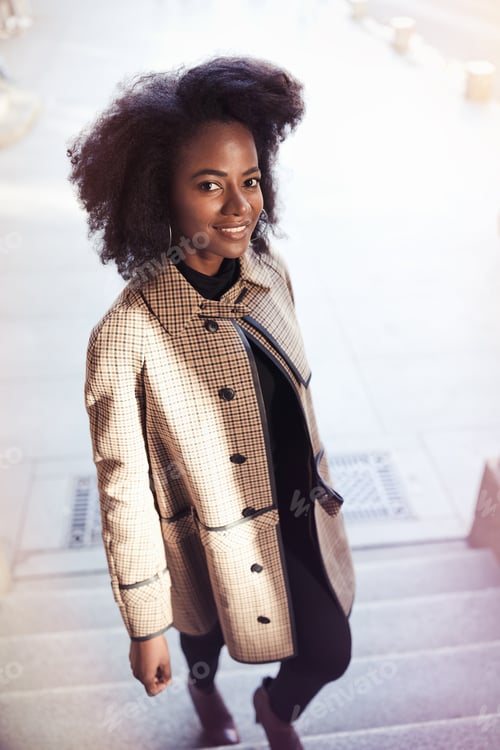 Preview: Beautiful African American woman outdoors in coat. Spring or fall time