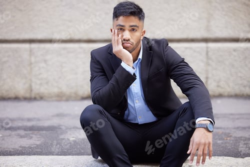 Preview: Shot of a handsome young businessman sitting and looking bored in the city