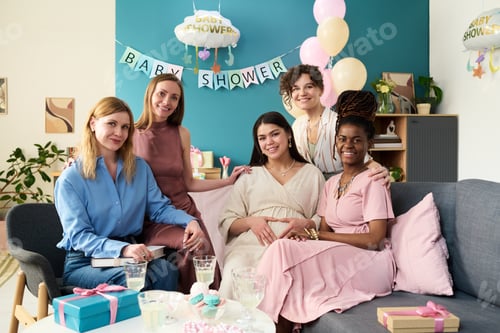 Preview: Happy young pregnant Caucasian woman holding belly surrounded by friends celebrating event