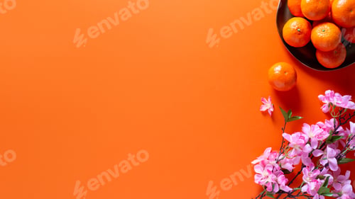 Preview: Chinese or lunar new year flat lay with plate of mandarins, pink flowers on orange, top view