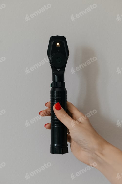 Preview: Handheld direct ophthalmoscope held by doctor showing close view of device