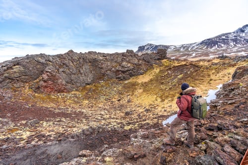 Preview: A hiker with a backpack in the Saxholl Crater volcano crater in winter in Iceland, Snaefellsnes