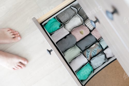 Preview: Organizing socks drawer and feet from above, high angle photo, chest of drawers, folding socks, tidy
