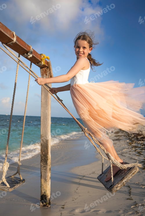 Preview: Beautiful girl on a swing near the sea. Summer fun, summer school break joy, candid childhood