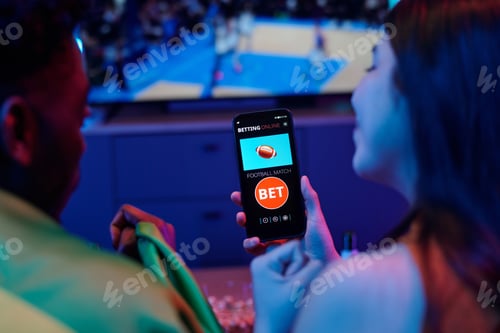 Preview: Young Caucasian Woman and Black Man Using Smartphone for Online Sports Betting