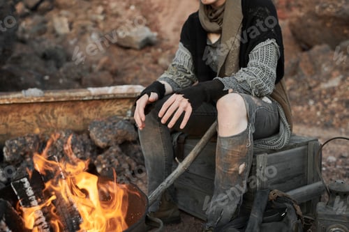 Preview: Homeless woman sitting near the fire outdoors