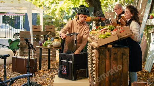 Preview: Young delivery woman with bag picking up veggies order