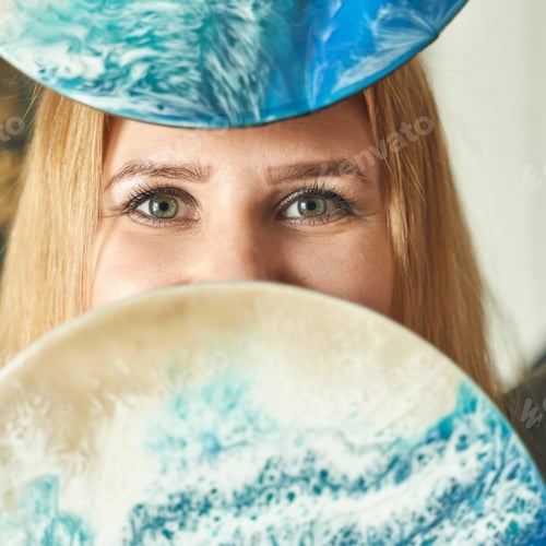 Preview: Young caucasian female artist with blue and beige abstract art pieces covering