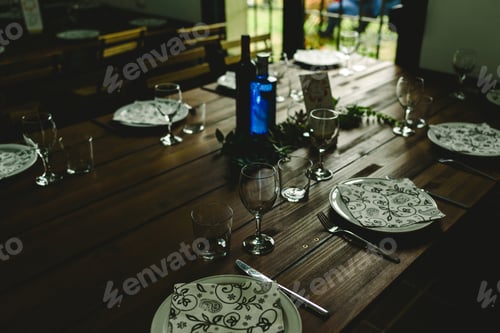 Preview: Wooden tables with cutlery plates and backlit glasses without anyone.