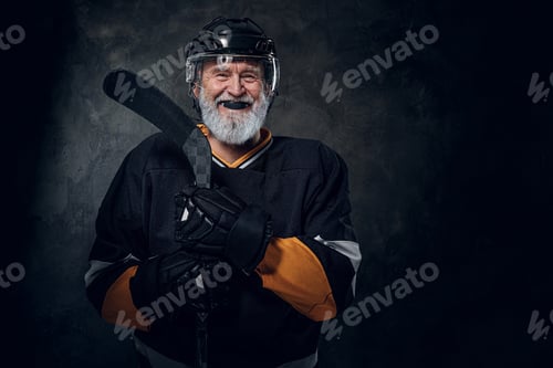 Preview: Joyful elderly hockey player with hockey stick dressed in uniform