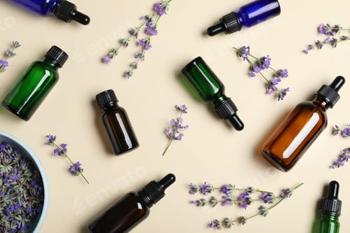 Preview: Bottles of essential oil and lavender flowers on beige background, flat lay