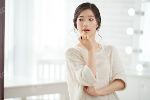 Woman Applying Lipstick in Front of Mirror