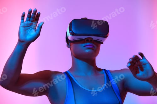 Preview: African american woman streamer playing video game using virtual reality glasses at gaming room