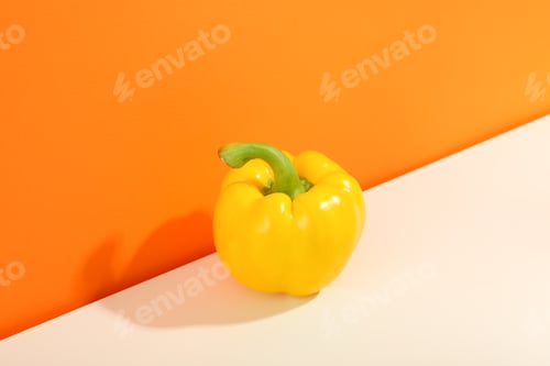 Bright Yellow Pepper on Orange and White Background