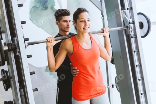 Preview: Young male trainer giving instructions to a woman in a gym