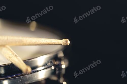 Preview: Close-up, snare drum and drumsticks on a dark background.