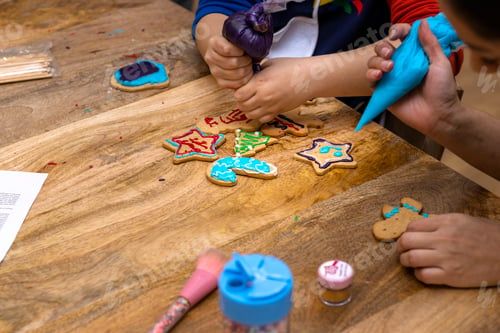 Preview: Christmas cookies workshop. Children decorating cookies with colorful pastry bags.