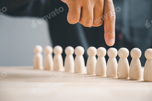 Preview: Finger pointing at one of a row of wooden figures. Concept of choosing the best candidate.