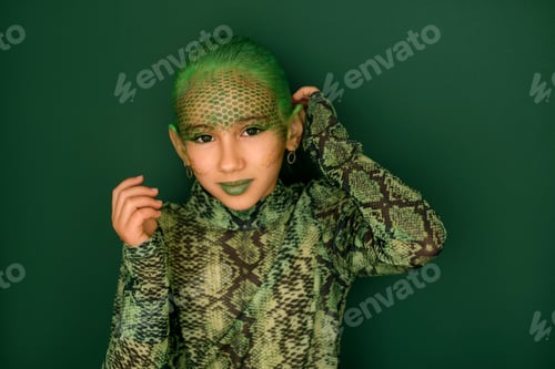 Preview: A teenage girl in the guise of a snake, with a face painted with paints and hair dyed green.