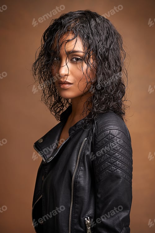 Preview: Studio shot of an attractive young woman in a leather jacket against a brown background