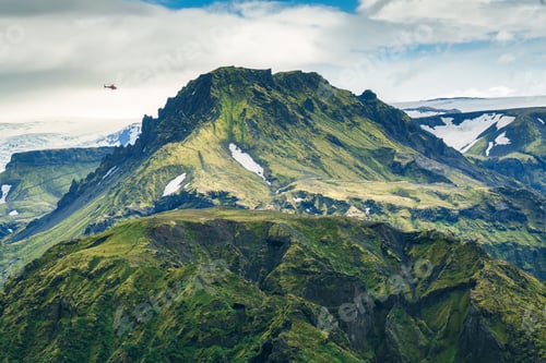 Preview: Lush rugged volcanic mountain with helicopter flying in Icelandic highlands at Thorsmork