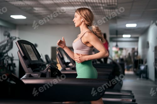Preview: Caucasian woman running on treadmill at fitness center