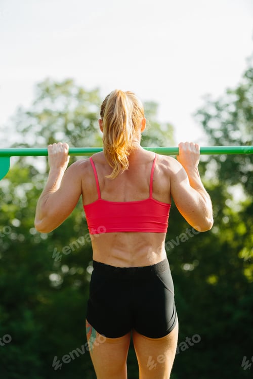 Preview: Woman exercising outdoors doing pull-ups