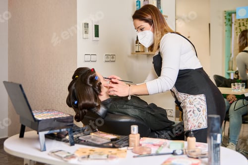 Preview: young hairdresser putting makeup on a woman in a beauty salon