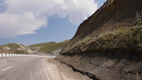 Preview: An empty road in the mountains. Action. View from the car to the road in a quiet place with green