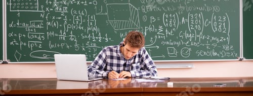 Preview: a young male teacher sitting at the table near blackboard and check the exam works of pupils