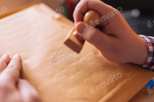 Vista previa: Man putting stamp on envelope ready to send mail