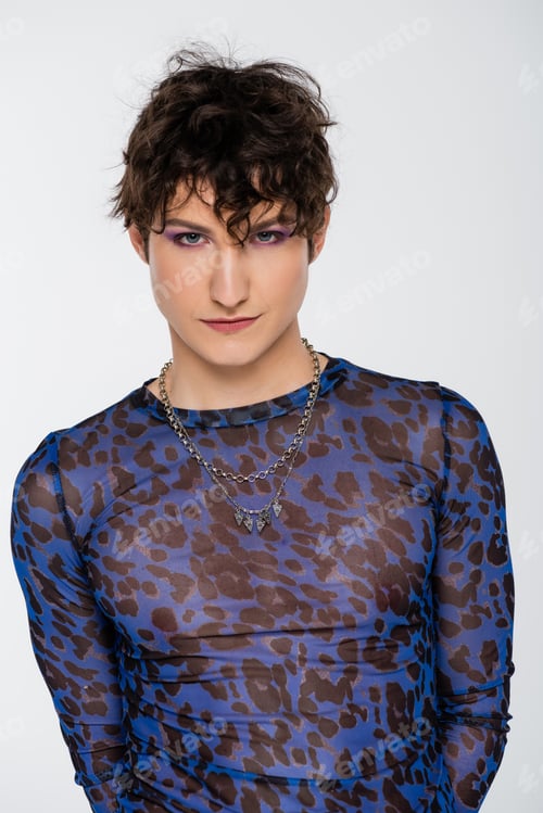 Preview: brunette nonbinary model in long sleeve shirt and silver necklaces looking at camera isolated on
