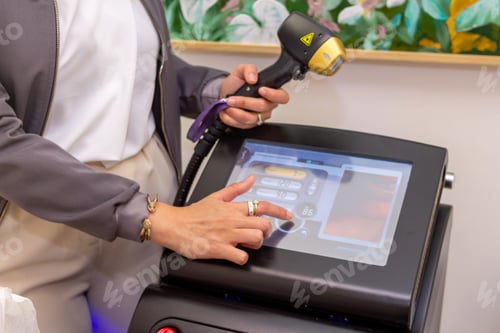 Preview: Closeup shot of a woman holding a laser hair removal device pressing the touch screen