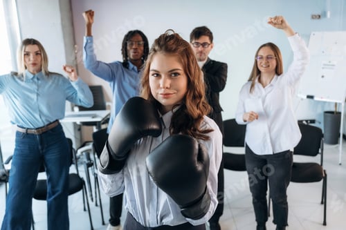 Preview: Having fun with boxing gloves. Group of young business people are in conference room
