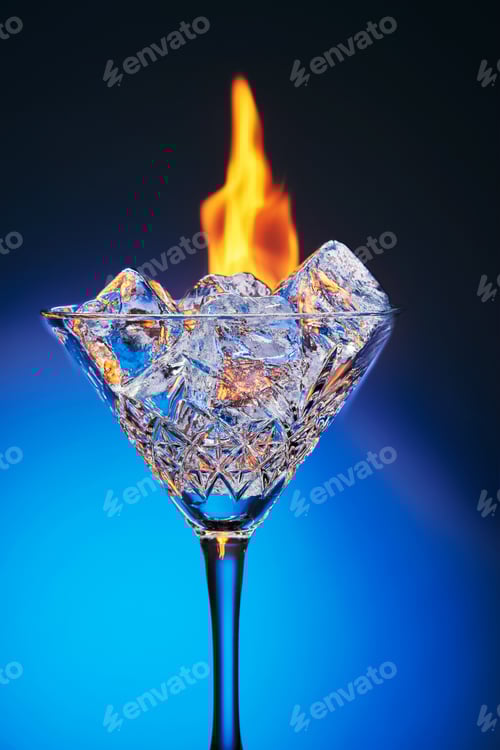 Preview: Ice in a martini glass and burning fire on a blue background with reflection and gradient