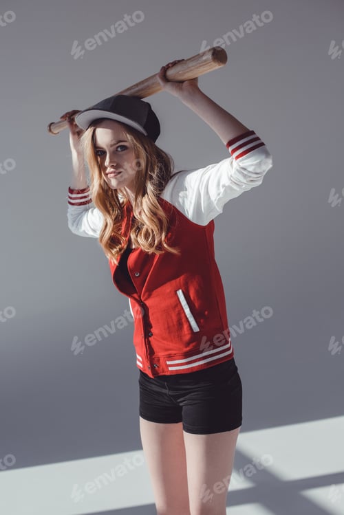 Preview: Attractive young sporty woman posing with baseball bat on grey