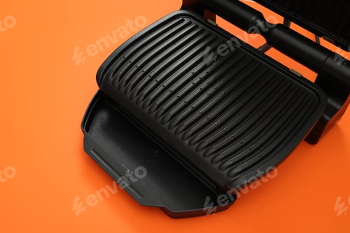 Preview: Electric grill on orange background, space for text. Cooking appliance