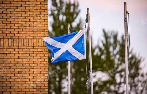 Preview: Scotland flag blowing in the wind in front of a red brick building