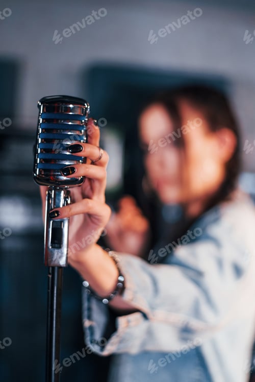 Preview: Close up view of microphone. Young beautiful female performer rehearsing in a recording studio