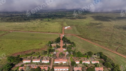 Preview: Aerial view of farmlands in Angola showcasing rural homes and agricultural fields under a cloudy sky