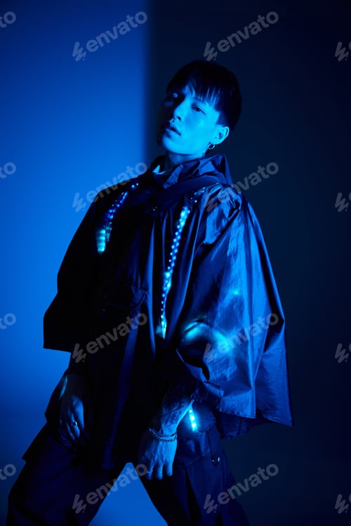 Preview: Stylish young man posing in blue lit ambiance showcasing modern fashion trends