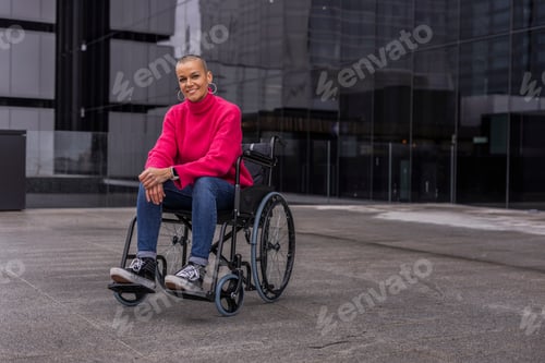Preview: Smiling businesswoman sitting on wheelchair outside modern office building