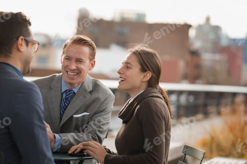 Preview: Three people standing in an open space between city buildings,talking to each other