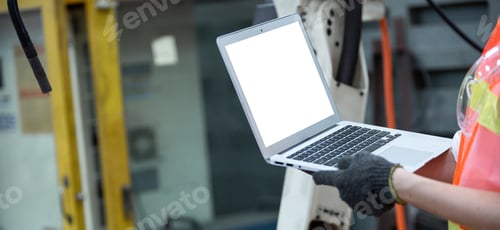 Preview: Hand of factory worker working on laptop with blank screen