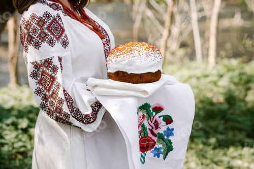 Preview: Ukrainian woman holding in hands Easter cake. Lady in embroidery vyshivanka dress on nature