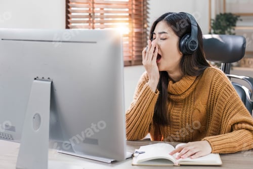 Preview: Tired teen asian lady in headphones falls asleep at table with laptop in room interior. Boring video