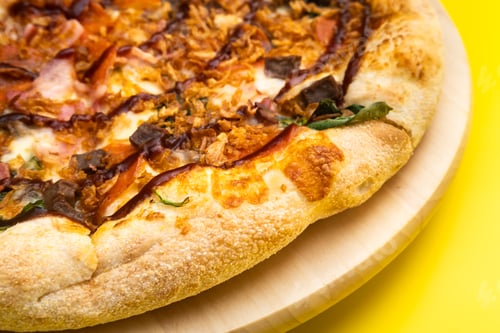 Preview: Delicious large pizza with bacon and spinach on a yellow background